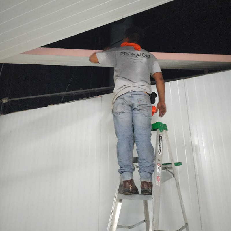 Trabajador en escalera haciendo la instalación de un cuarto frío